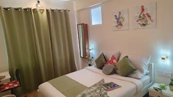 A hotel room with a bed, a chair, a bedside table, and a window.