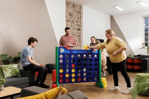 Eine Gruppe spielt ein Spiel mit einem blaugrünen Spielbrett in einem modernen Innenraum.