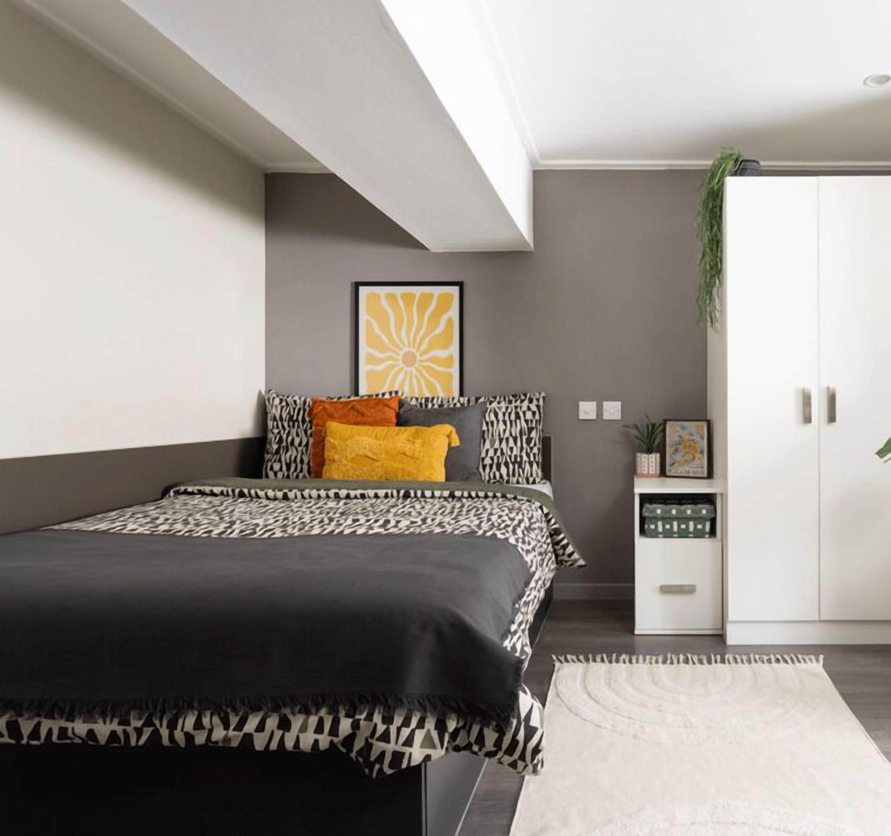 Une chambre à coucher moderne, avec un lit, une table de chevet, une armoire et une plante fixée au mur.