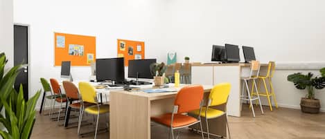 A modern office space with a long table, multiple chairs, and computers.