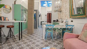 Una cocina funcional con comedor, que presenta un piso estampado, armarios verdes y una mesa con sillas.