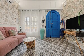 A living room with a sofa, a coffee table, a TV, and a blue door. - El Mar Azul 1 Beachfront Apartment, Wi-Fi, Air Conditioning (Torremolinos)