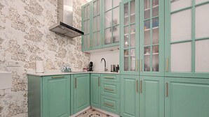 A kitchen with teal cabinets, a patterned backsplash, and a tiled floor. - El Mar Azul 5 Beachfront Family Apartment (Torremolinos)