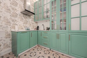 A kitchen with teal cabinets, a patterned backsplash, and a tiled floor. - El Mar Azul 5 Beachfront Family Apartment (Torremolinos)