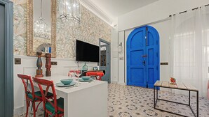 A dining area with a white table, red chairs, and a blue door in the background. - El Mar Azul 5 Beachfront Family Apartment (Torremolinos)