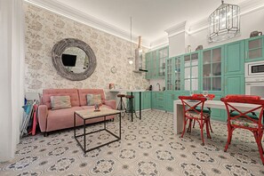 A room with a sofa, a coffee table, a dining table with chairs, and a kitchen area with cabinets and a stove. - El Mar Azul 5 Beachfront Family Apartment (Torremolinos)