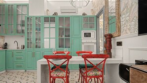 A kitchen with teal cabinets, a white countertop, and red chairs with floral cushions. - El Mar Azul 5 Beachfront Family Apartment (Torremolinos)