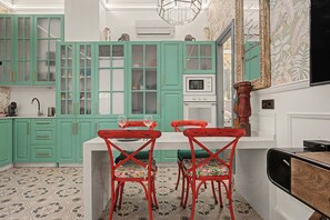 A kitchen with teal cabinets, a white countertop, and red chairs with floral cushions. - El Mar Azul 5 Beachfront Family Apartment (Torremolinos)