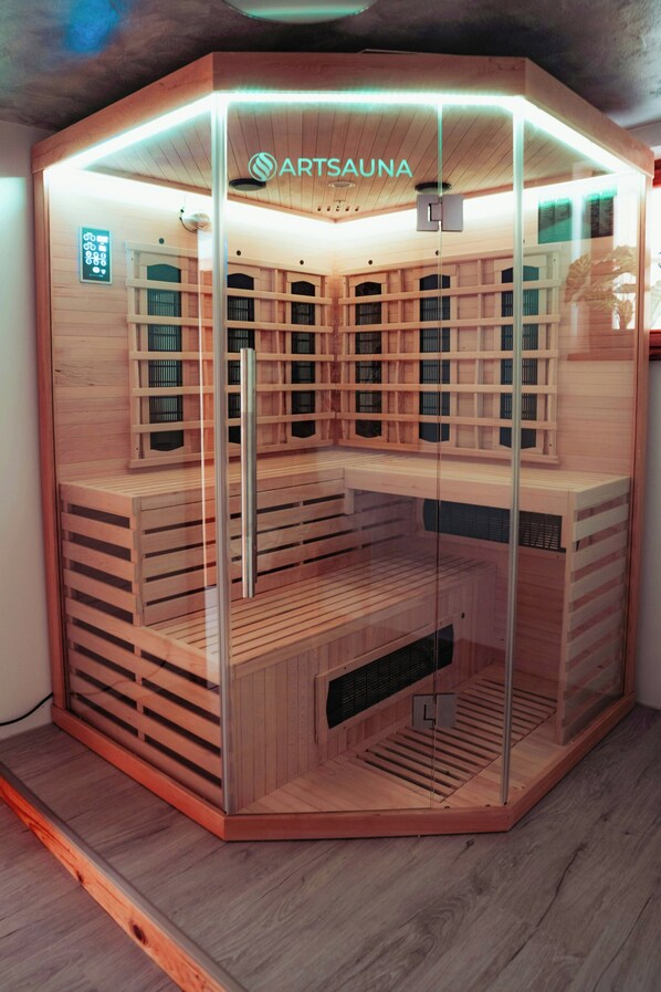 A sauna with a wooden interior, glass walls, and a sign that reads 'ARTSAUNA'.