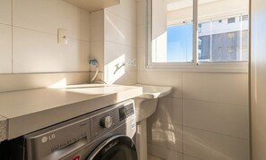 Ein Waschbereich mit Waschmaschine, Spüle und Fenster.