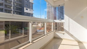A balcony with large windows, a tiled floor, and a view of surrounding buildings. - Apartment in a Condominium in Setor Bueno Lhd0403 (Goiânia)