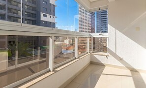 Ein Balkon mit großen Fenstern, gefliestem Boden und Blick auf umliegende Gebäude.