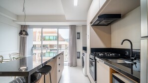 Uma cozinha moderna com ilha central, bancadas pretas e eletrodomésticos de aço inoxidável.
