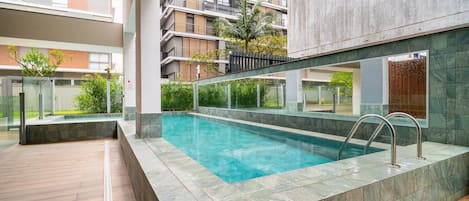 A modern indoor swimming pool with clear water, surrounded by a tiled deck and glass barriers.
