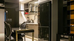 A modern kitchen with a black refrigerator, a coffee maker, and a dining area with a black chair and table. - Modern Duplex W/jacuzzi 240m Beach Jrr410 (Florianópolis)