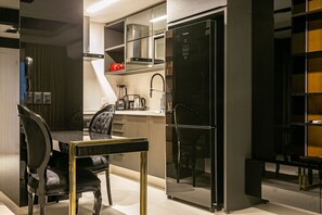 A modern kitchen with a black refrigerator, a coffee maker, and a dining area with a black chair and table. - Modern Duplex W/jacuzzi 240m Beach Jrr410 (Florianópolis)