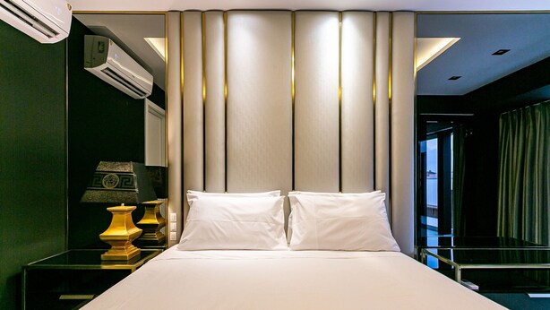 A hotel room with a large bed, a bedside table with a lamp, and an air conditioning unit. - Modern Duplex W/jacuzzi 240m Beach Jrr410 (Florianópolis)