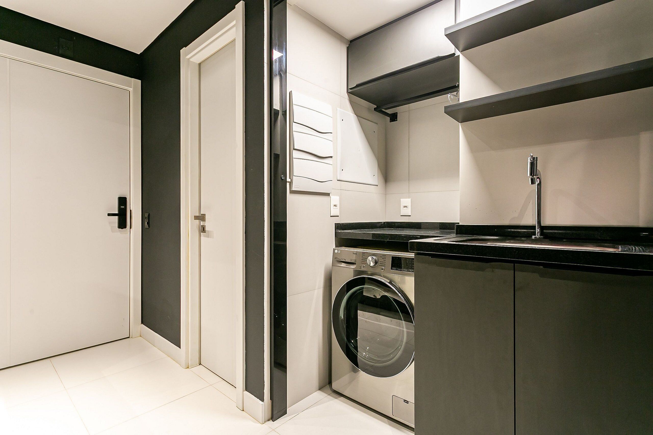 A compact laundry room with a washing machine, a sink, and a door.