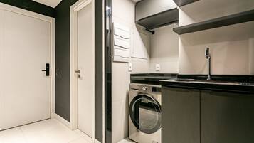 A compact laundry room with a washing machine, a sink, and a door.