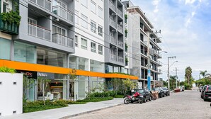 A modern building with multiple floors, balconies, and a storefront with signage. - Modern Duplex W/jacuzzi 240m Beach Jrr410 (Florianópolis)