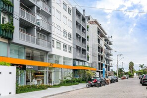 A modern building with multiple floors, balconies, and a storefront with signage. - Modern Duplex W/jacuzzi 240m Beach Jrr410 (Florianópolis)