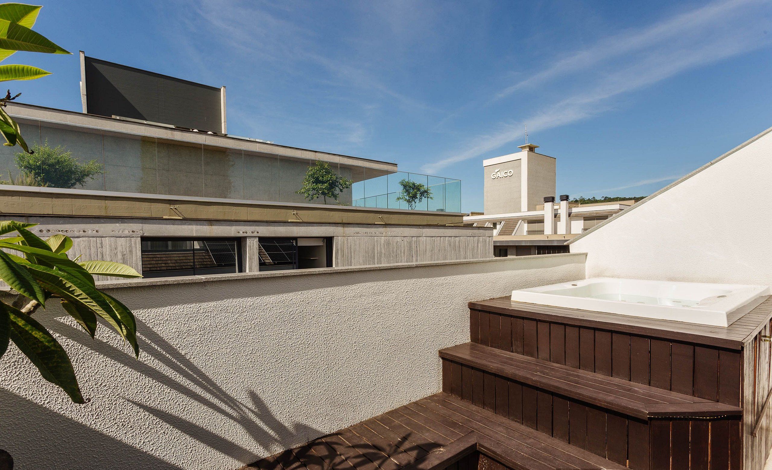 Terraza en la azotea con jacuzzi, un edificio moderno y cielo despejado.