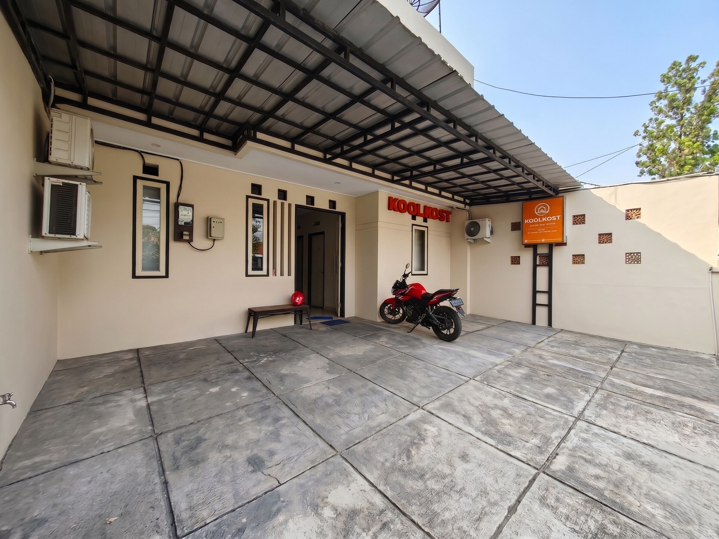 Um edifício com uma placa indicando 'KOOLKOST' e uma motocicleta estacionada na frente.