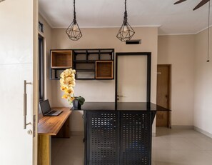 A modern kitchen with a wooden countertop, a black island, and pendant lighting.