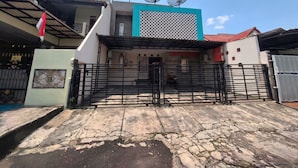 A gated entrance with a metal gate, a satellite dish on the roof, and a building with a patterned facade.