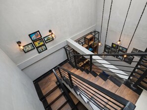 A multi-level interior with a staircase, wooden flooring, and wall-mounted lighting fixtures.