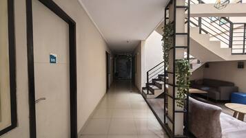 Corredor de hotel com escada, sofá e planta.