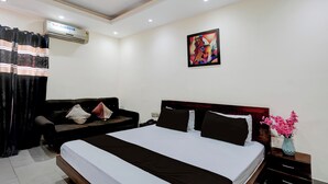 A hotel room with a bed, a sofa, a painting on the wall, and an air conditioning unit. - Collection O Bus Terminal Haldwani (Haldwani)