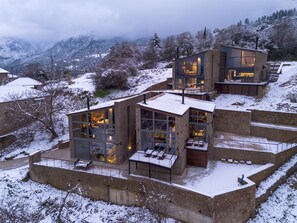 A modern multi-story building with large windows and a stone facade, surrounded by a snowy landscape.