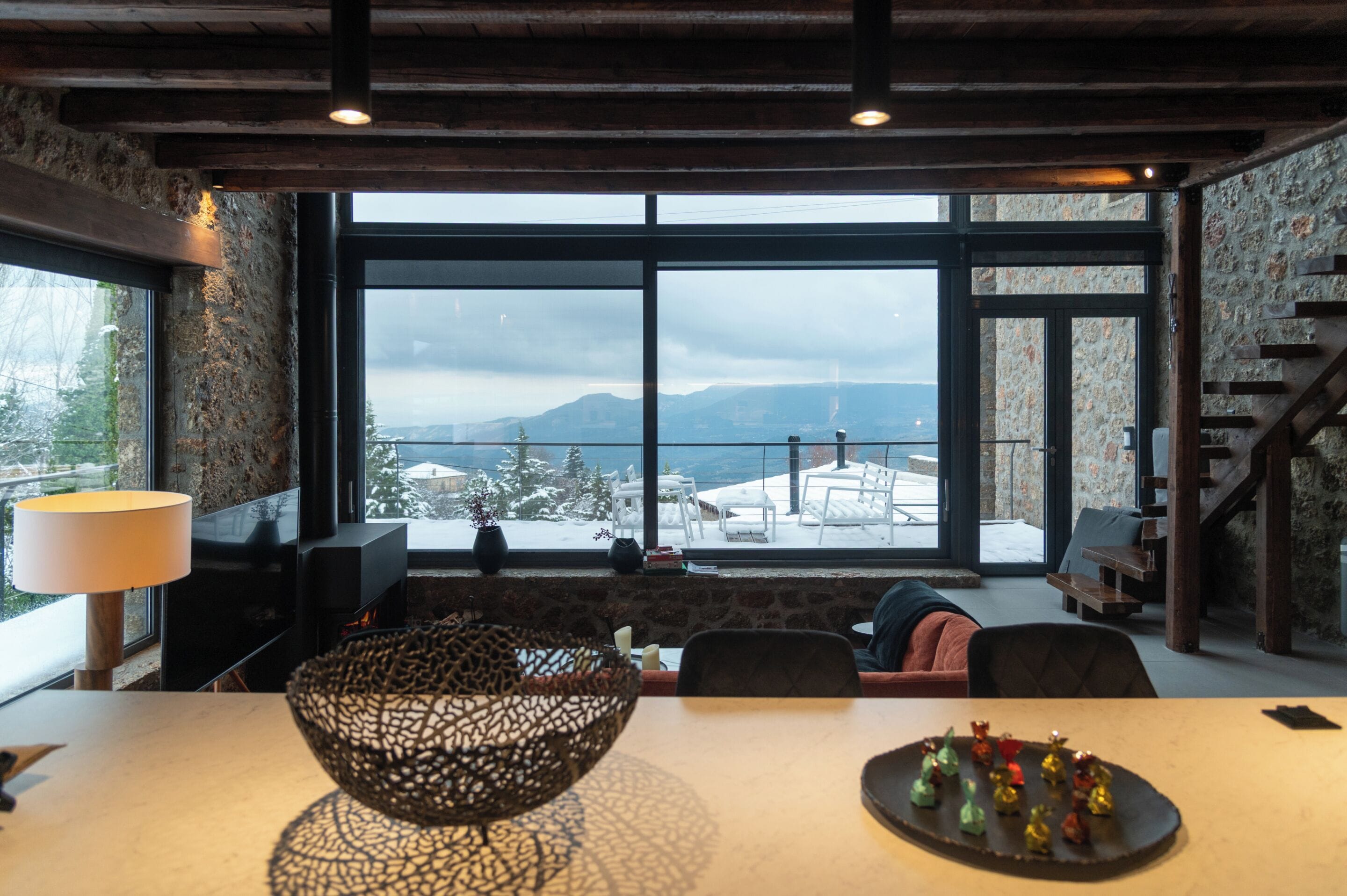 Un interior moderno con un ventanal que ofrece vistas a montañas nevadas.