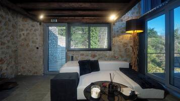 A room with a large window, a sofa, a table with candles, and a lamp.