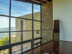 Quarto com uma grande janela, parede de pedra e piso de madeira.