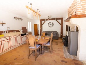 A cozy kitchen with a dining table, chairs, a clock, and a fireplace. - Gite du Plateau, House for 6 People (Saint-Remèze)