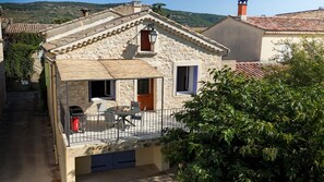 A stone building with a balcony, a table, and chairs. - Gite du Plateau, House for 6 People (Saint-Remèze)