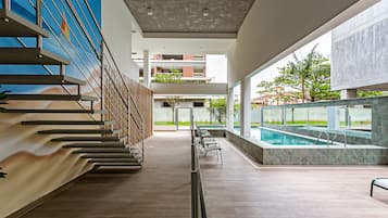 Uma área moderna de piscina interna com uma escada à esquerda e vista para edifícios externos.