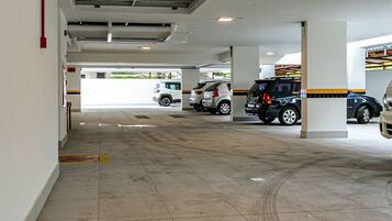 A parking garage with multiple levels and columns, featuring several parked cars.