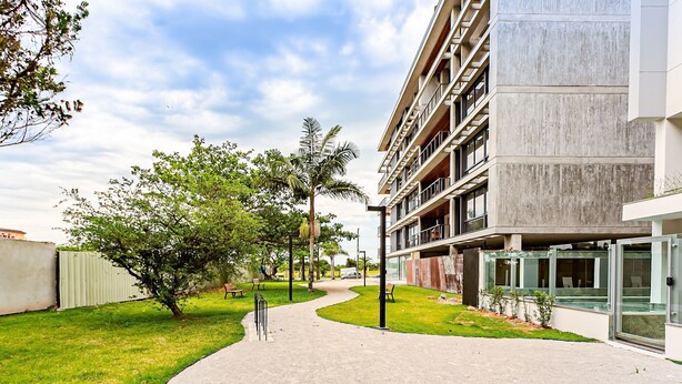 Un camino que lleva a un edificio moderno con fachada de concreto y varios balcones.
