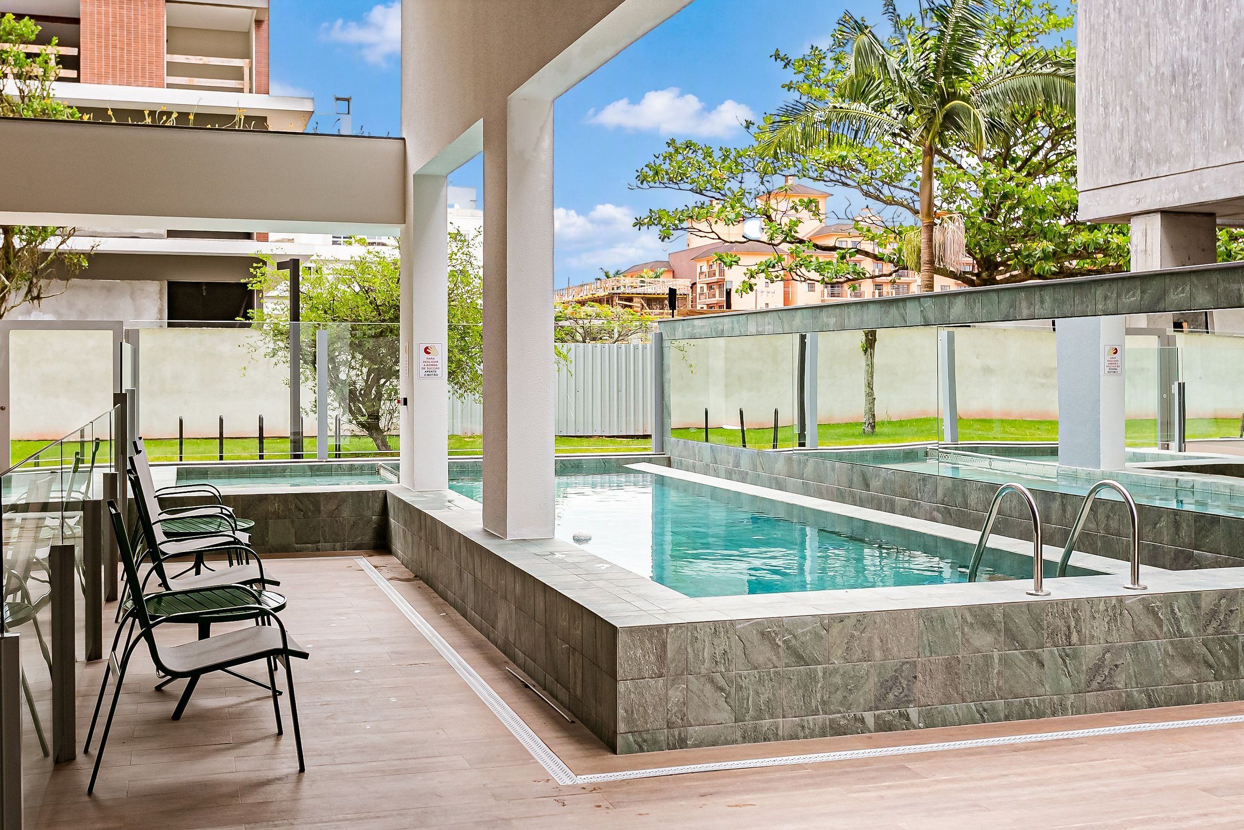 Un área de piscina moderna al aire libre con asientos y vistas de los edificios circundantes.