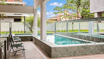 Un área de piscina moderna al aire libre con asientos y vistas de los edificios circundantes.