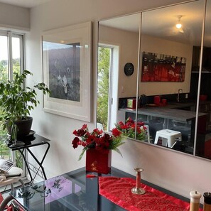 Una cocina moderna con una mesa de vidrio, camino de mesa rojo y una planta en maceta.