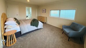 Een slaapkamer met een bed, een stoel, een kaptafel, een raam en een deur.