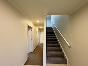 A carpeted staircase with a handrail leading to a door at the top. - Sunny Wānaka Home with Stunning Mountain Views (Wānaka)