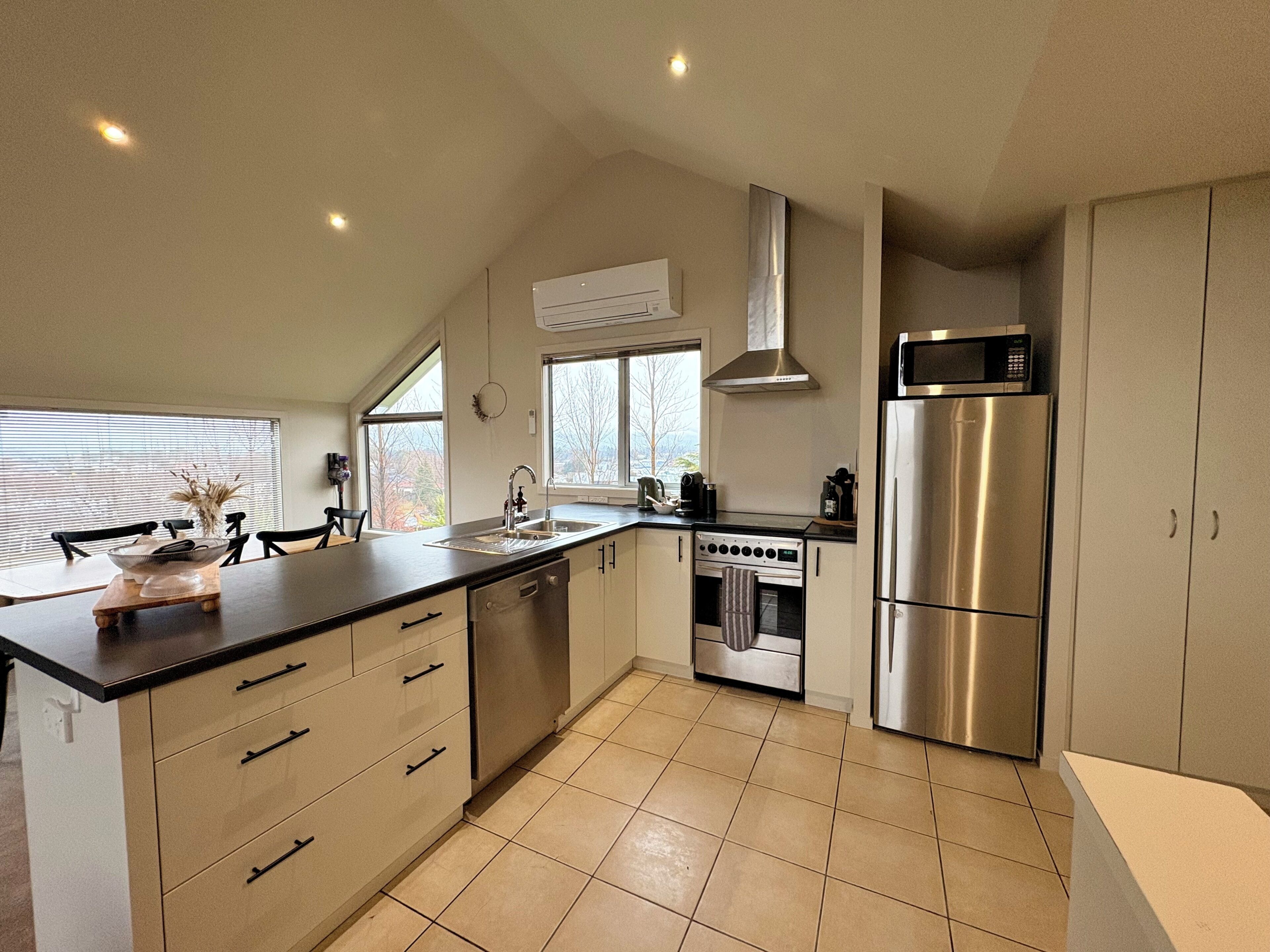 A modern kitchen with a large island, stainless steel appliances, and a view of the outdoors.