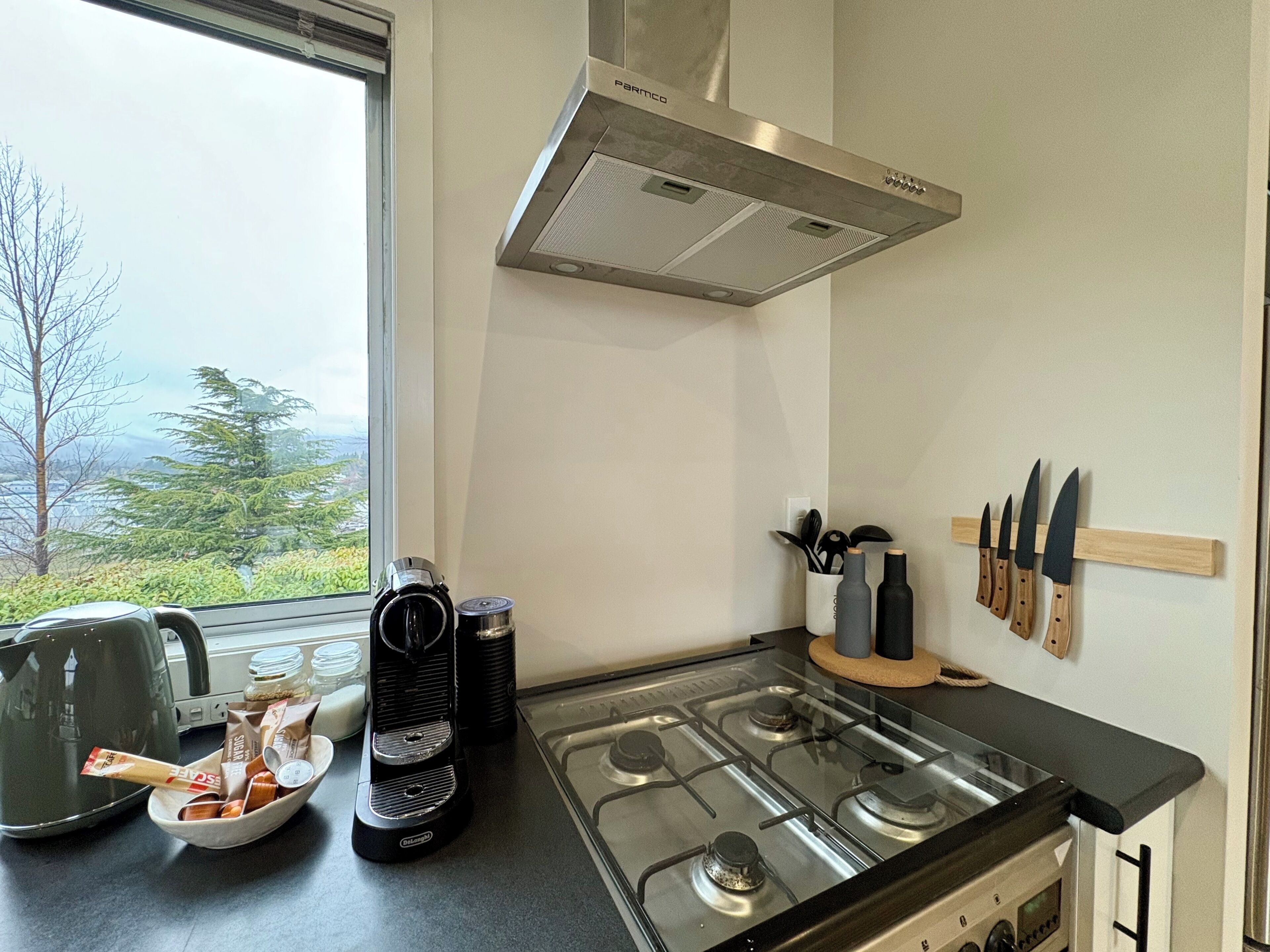 Una cocina con estufa a gas, cafetera y un soporte para cuchillos.