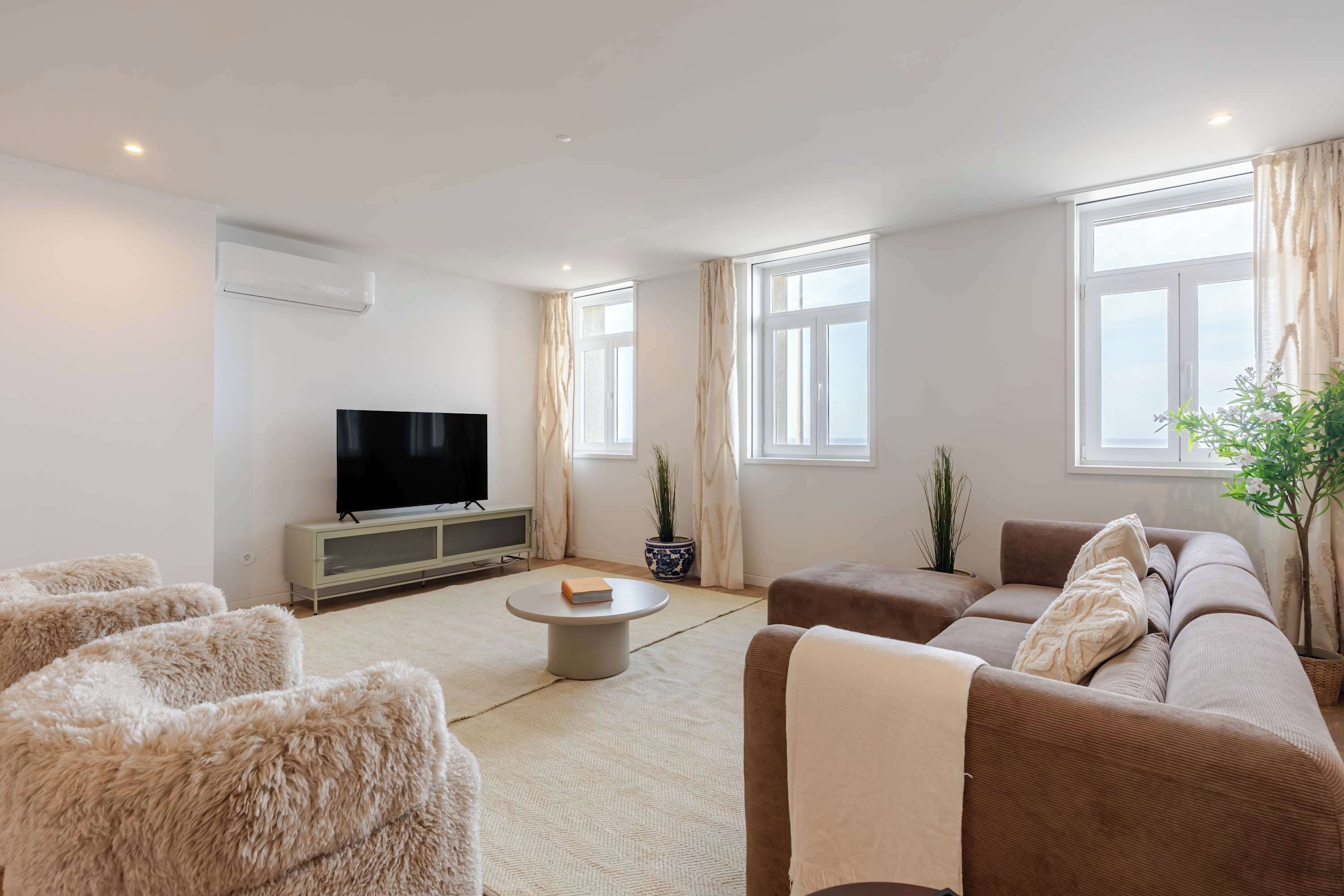 Una sala de estar moderna con un televisor de pantalla plana, un sofá, una mesa de centro y una alfombra mullida.