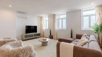 Una sala de estar moderna con un televisor de pantalla plana, un sofá, una mesa de centro y una alfombra mullida.